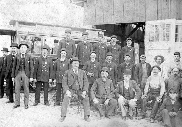 Staff of electric trolley company, Fort Wayne, at old horse-car barn, Glasgow & Washington, ca. 1890. Man in cap & braces, extreme right top is Frank Carbaugh