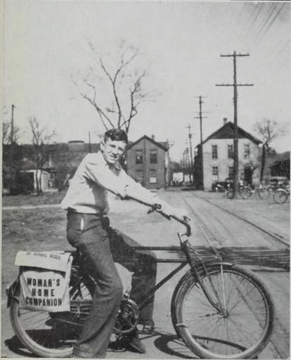 Boy on bike by railroad tracks going inbetween buildings